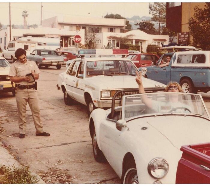 Vintage photo of a police officer writing a ticket while a woman in a convertible waves, capturing a moment in history. Vintage photo of a police officer writing a ticket while a woman in a convertible waves, capturing a moment in history.