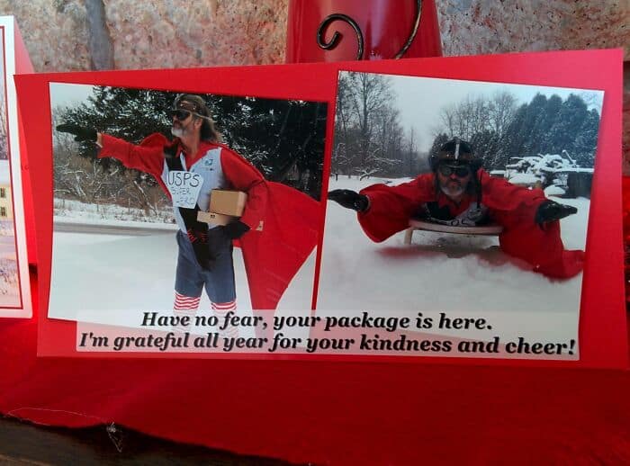 Funny Christmas card featuring a person dressed as a USPS superhero delivering packages in the snow.