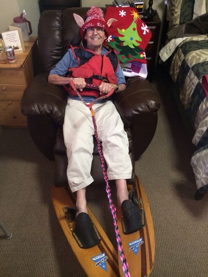Man in an elf hat on recliner with water skis, embodying funny Christmas card humor.
