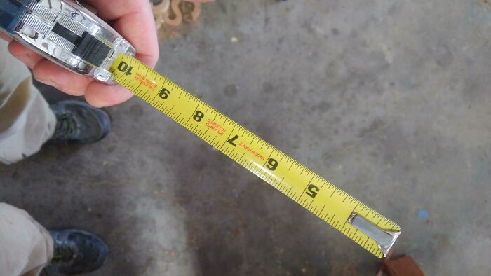 Person holding a tape measure showing a length on the floor, illustrating careless online shopping backfired measurement. Person holding a tape measure showing a length on the floor, illustrating careless online shopping backfired measurement.