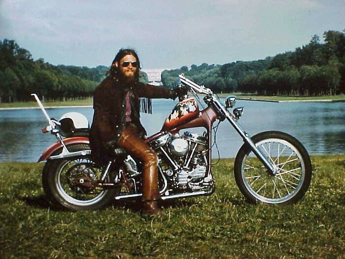 Man with sunglasses on a vintage motorcycle by a lake, capturing 1973 world in pictures vibe. Man with sunglasses on a vintage motorcycle by a lake, capturing 1973 world in pictures vibe.