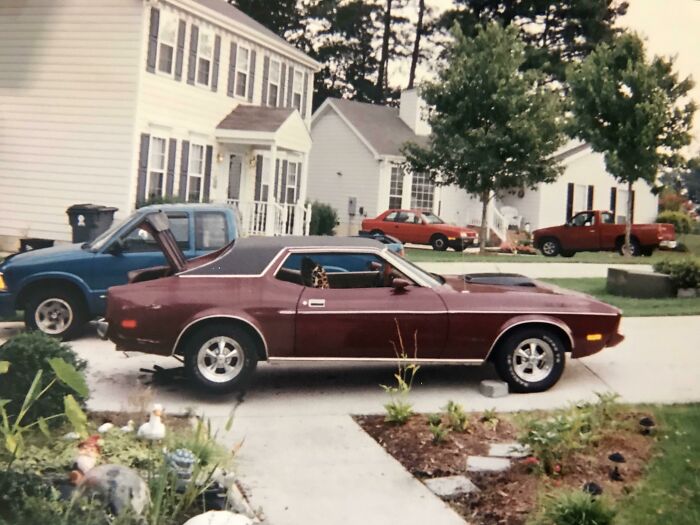1973 vintage car in a suburban driveway with houses and trees in the background. 1973 vintage car in a suburban driveway with houses and trees in the background.