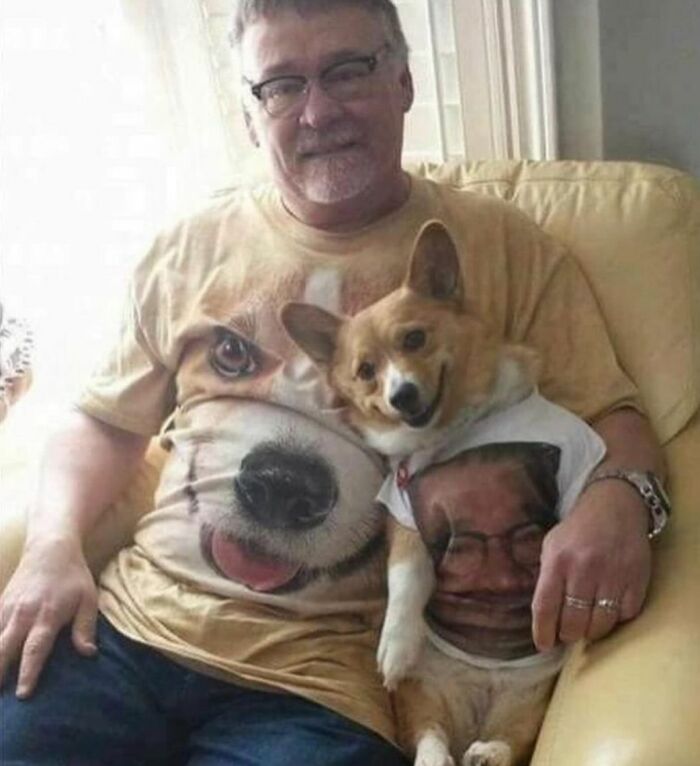 Man and corgi matching awkward photos t-shirts with dog and human faces sitting on a couch together Man and corgi matching awkward photos t-shirts with dog and human faces sitting on a couch together